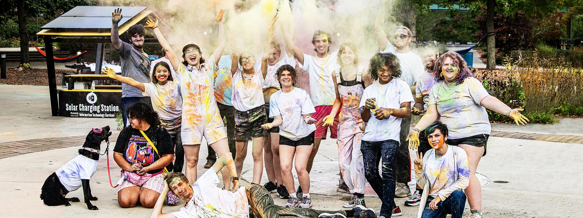 Students throw colorful chalk in the air after a color run on campus.