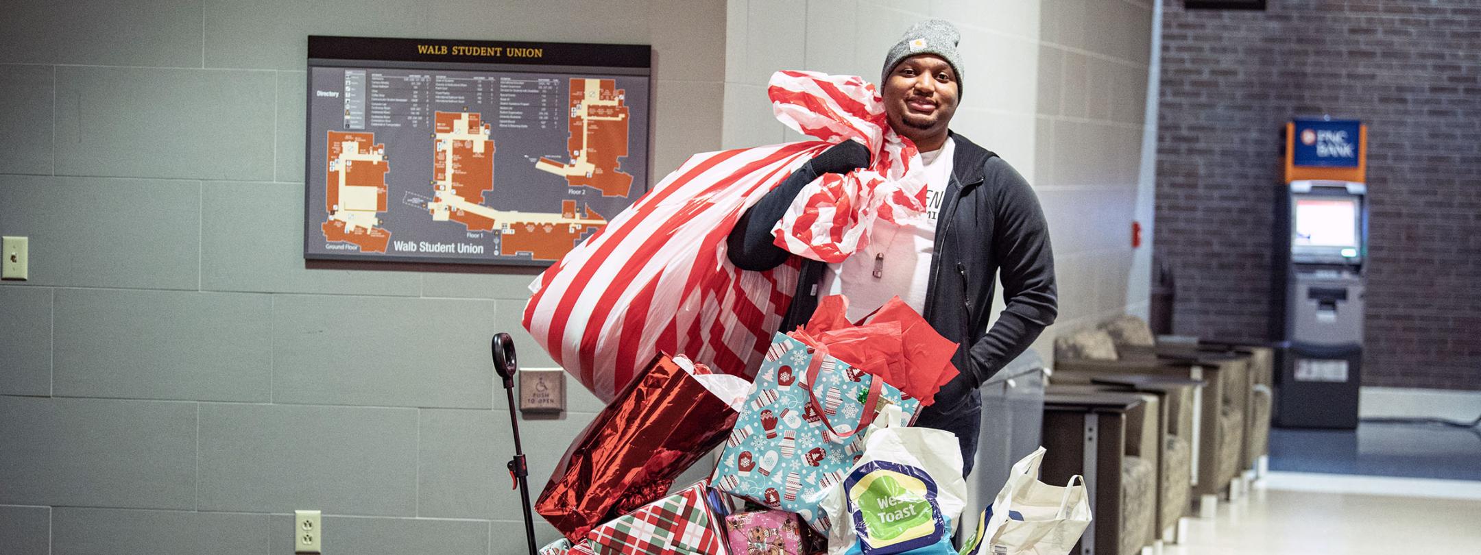 A man is standing beside a cart full of holiday gifts