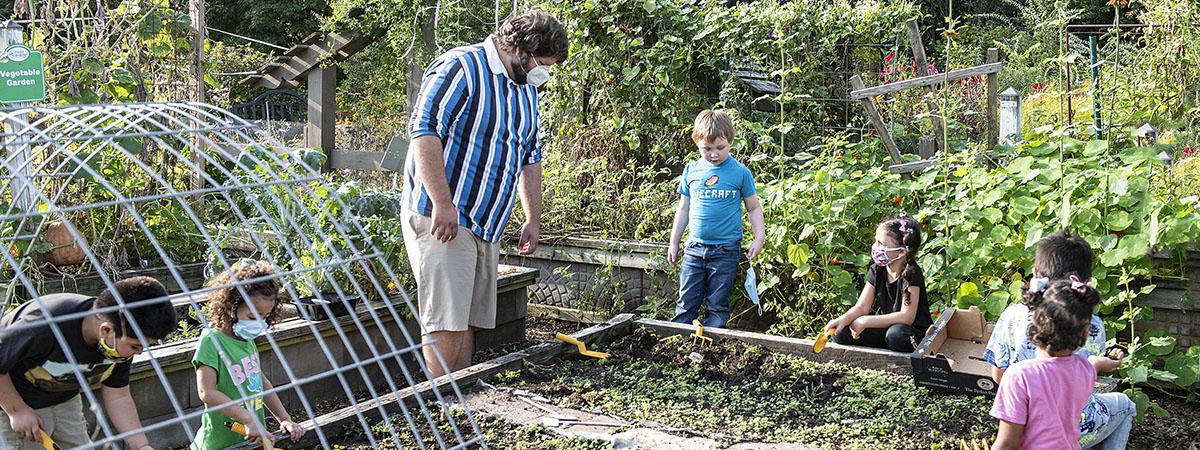 An adult and several children are working in the School of Education's urban garden.