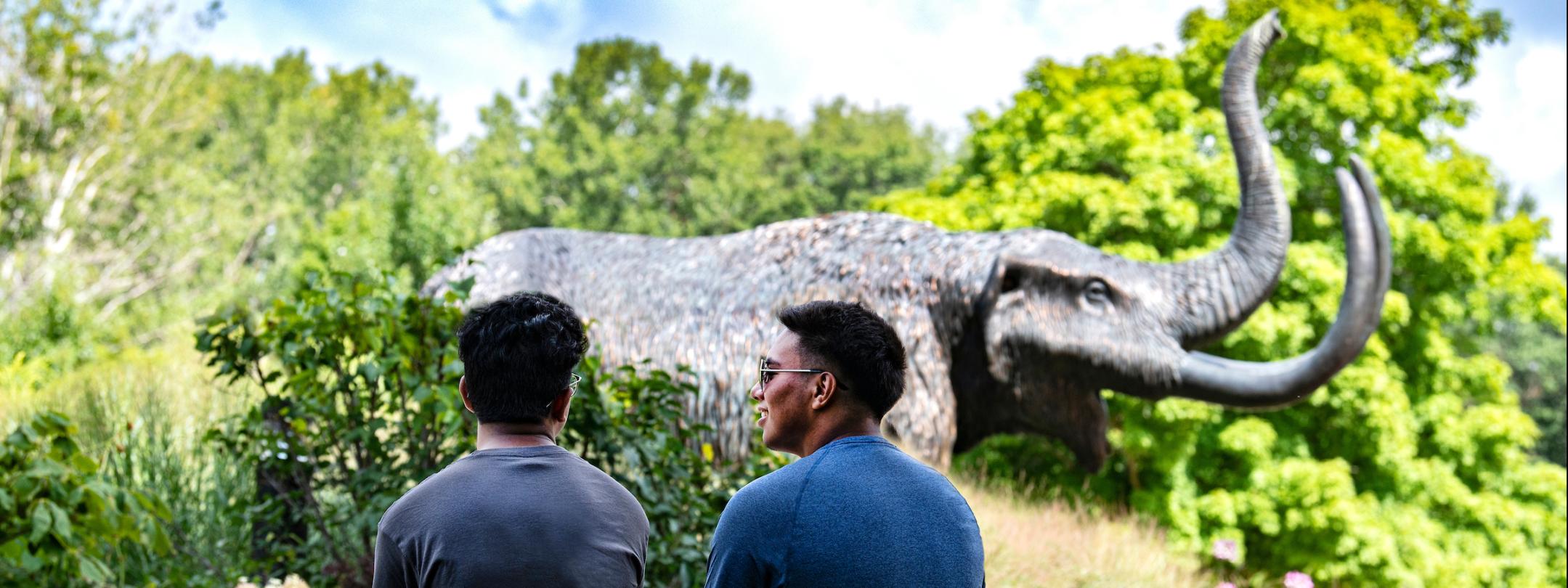 Two students site on a ledge near the Mastodon statue.