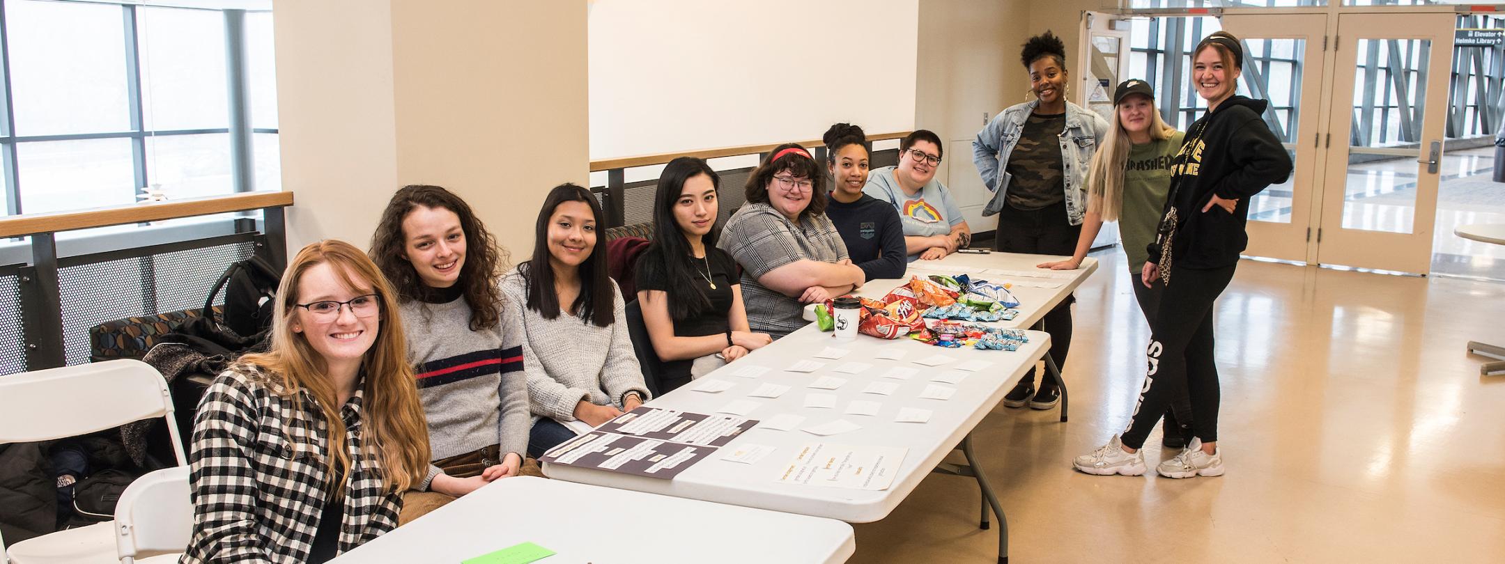 Students at a display table for a WOS event.