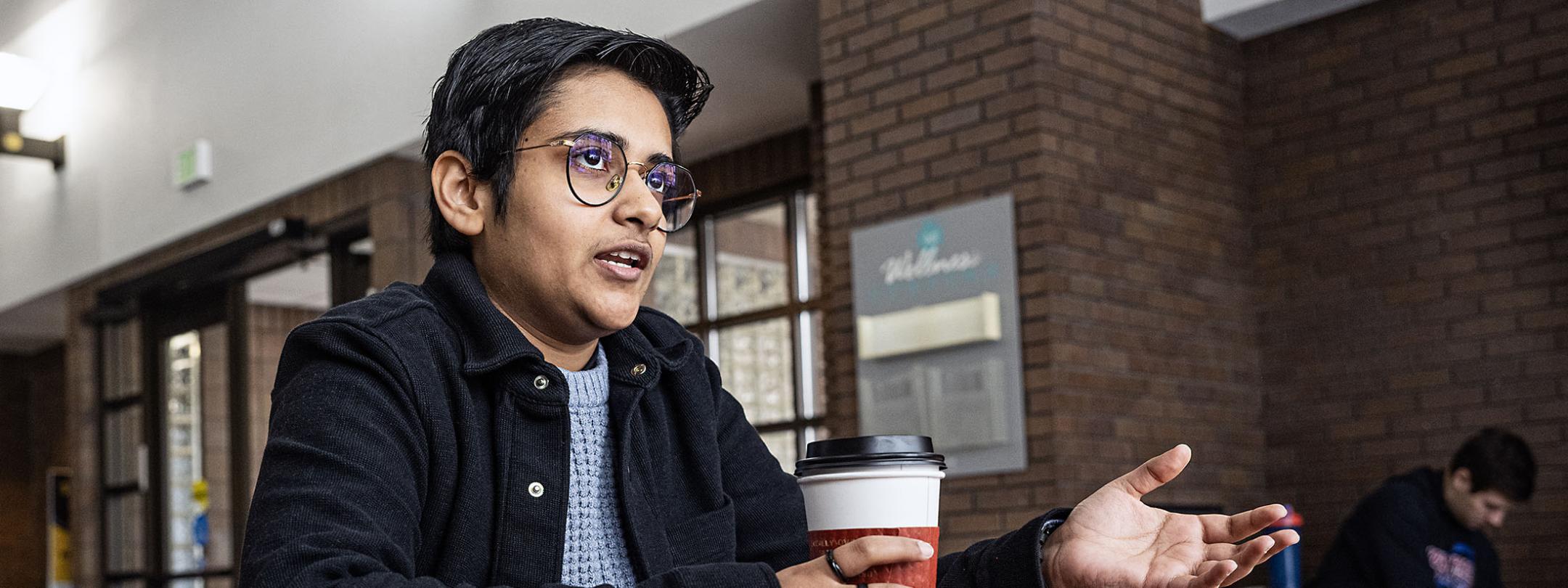 Yashi Yadav is sitting at a table and speaking to someone.