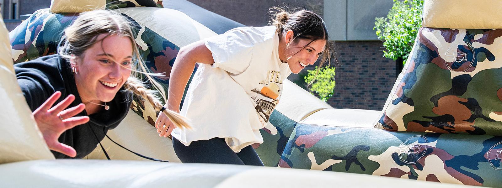 Two students are playing on a giant inflatable ride