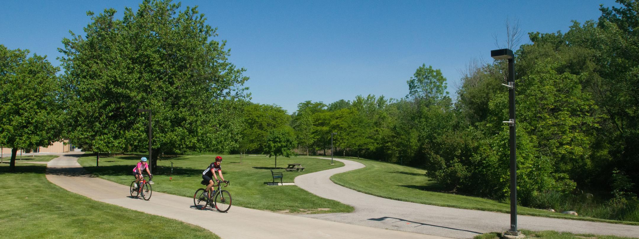 People riding bikes along the trail for the Native Tree Walk on campus.