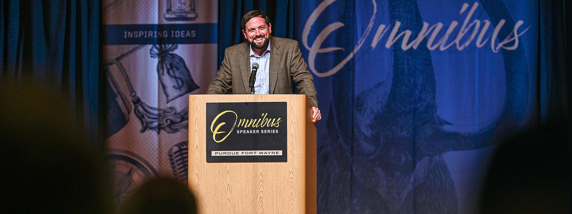 Luke Russert presents behind podium at Omnibus Speaker Series