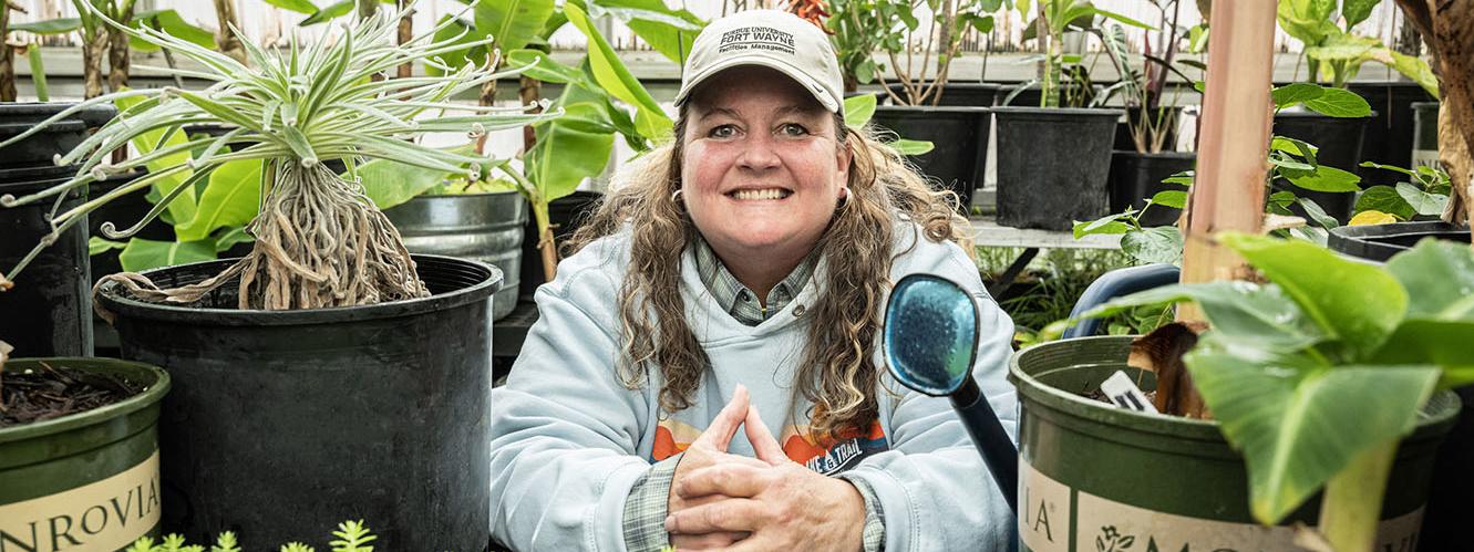 Holly Walters is surrounded by plants in a greenhouse