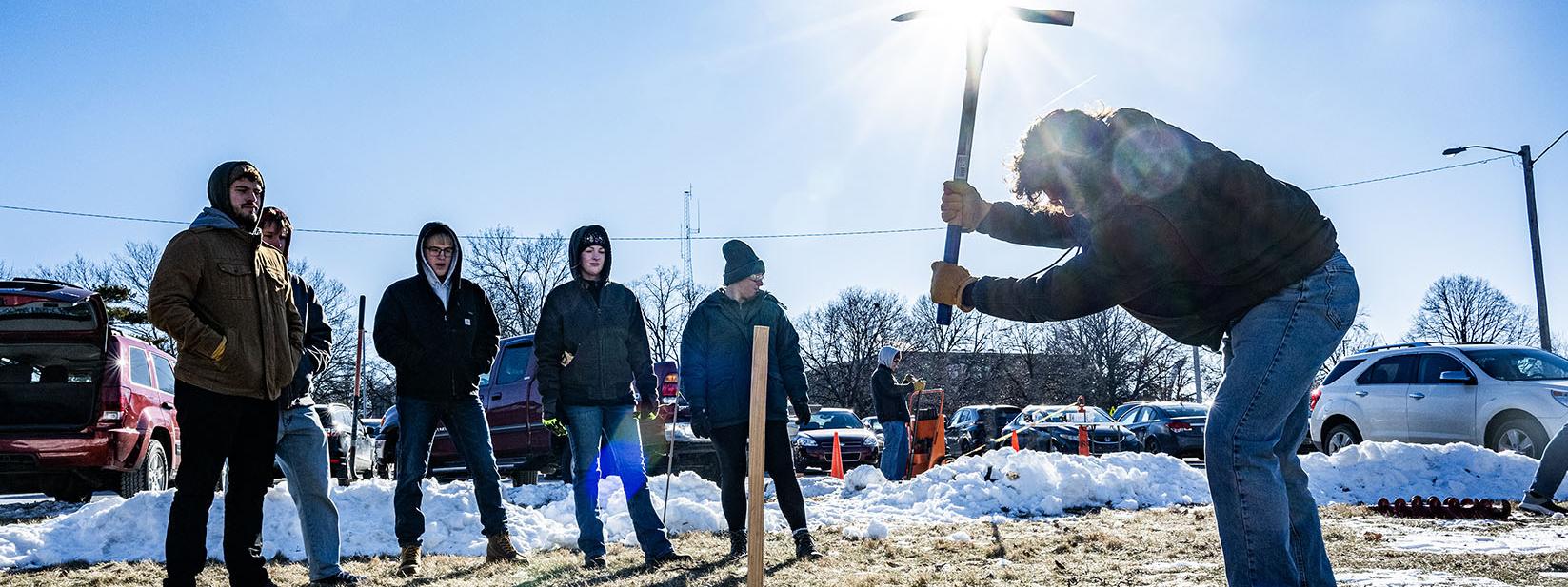 Civil Engineering students are using a pickaxe to take a soil sample