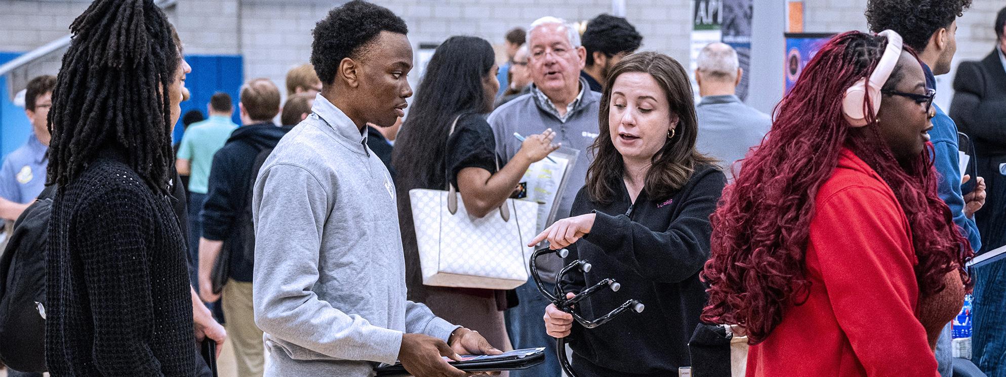 Students talking to an instructor in the fieldhouse