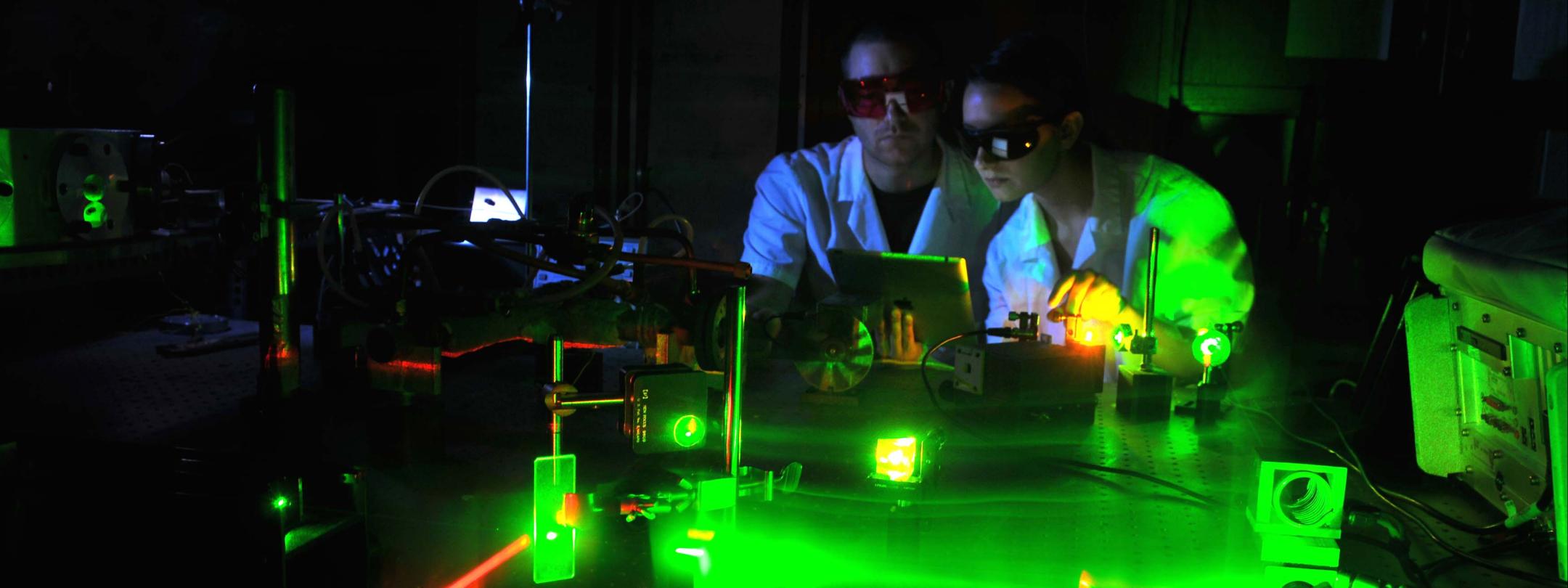 Physics student working with lasers in a laboratory setting.