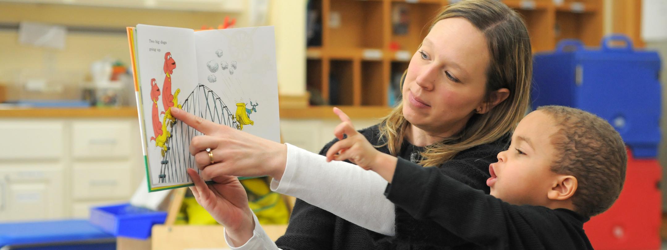 A female teacher share a book with a child