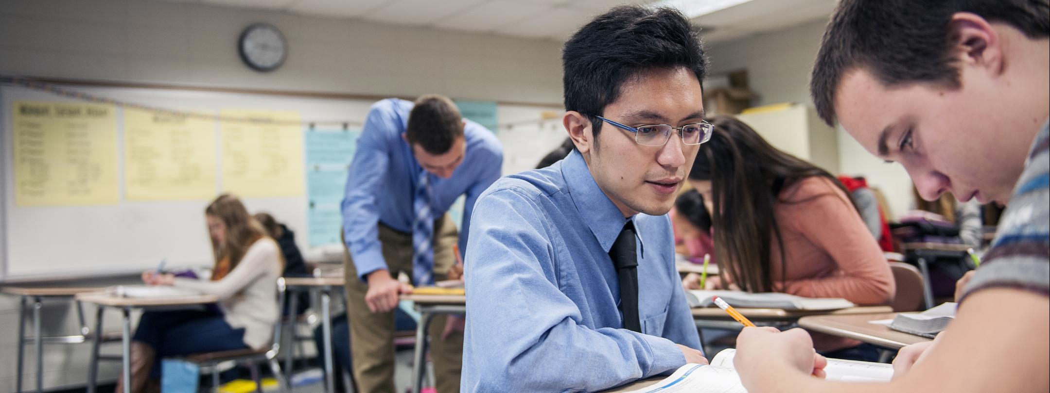 A male student teacher helps a high school student