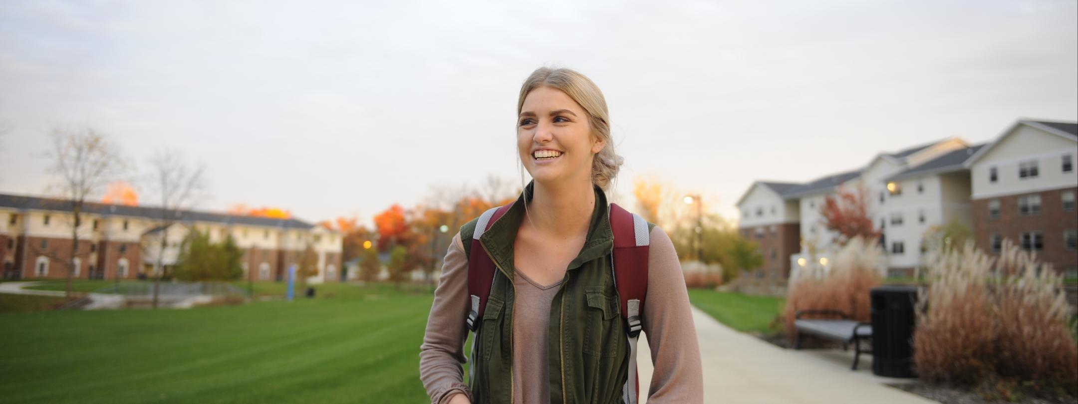 PFW female student walking on the grounds of student housing.