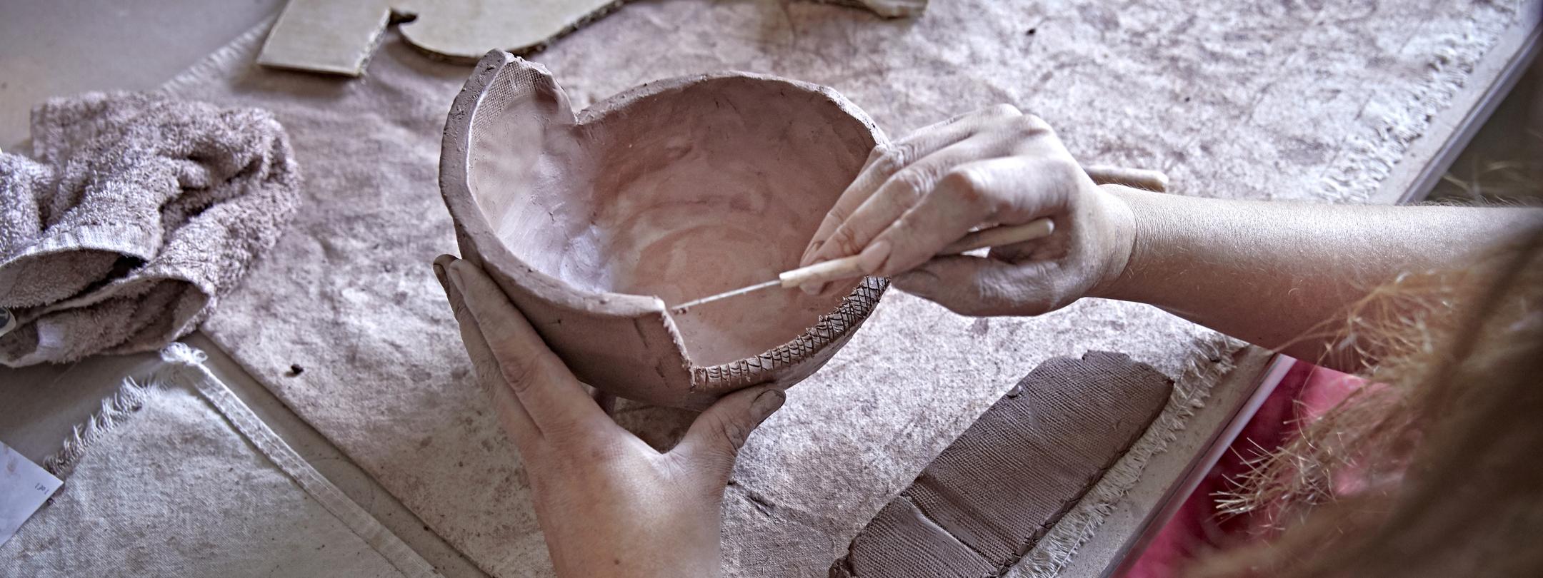 Close up of hands using a tool to work with a ceramics project