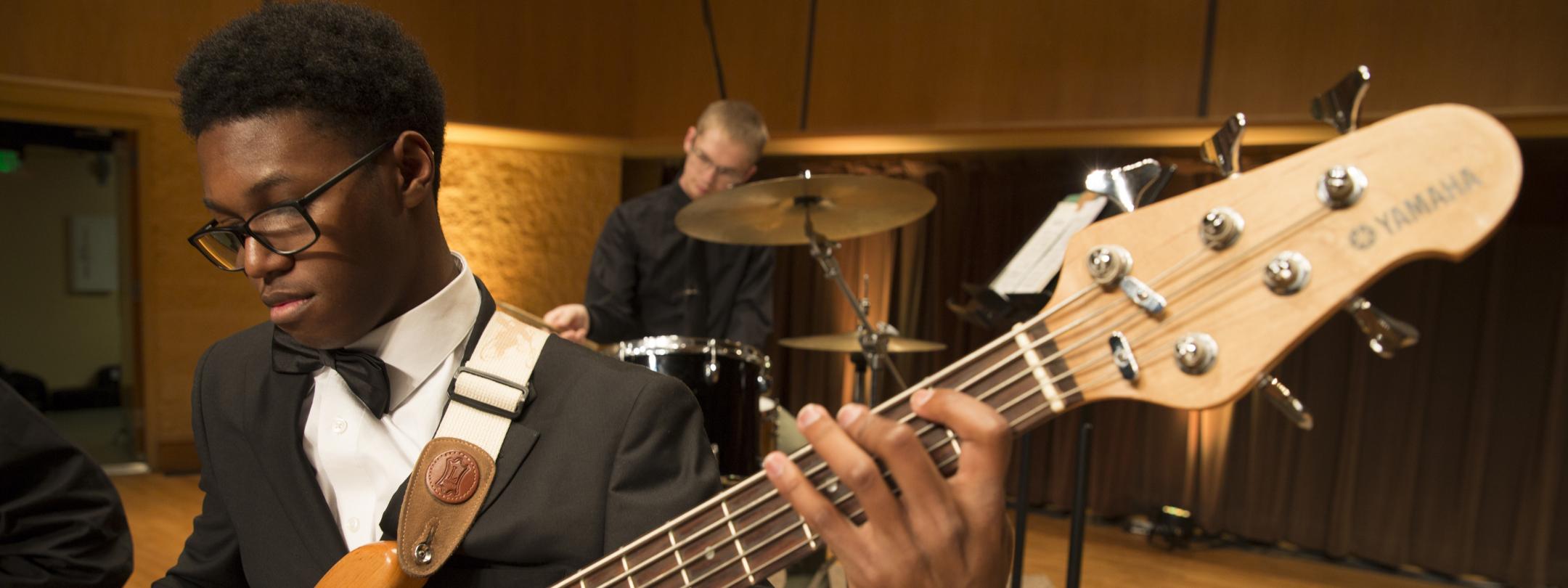 Student playing in a guitar in a concert.