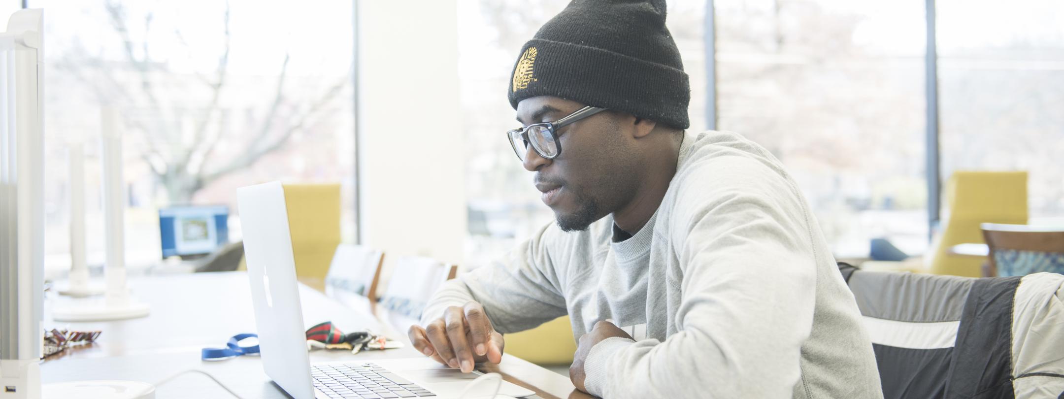 Student studying his class assignments on his laptop.