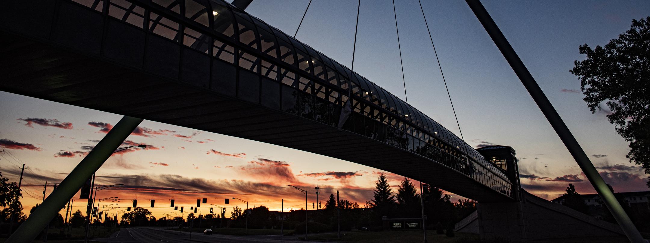 Sunset on campus with the silhouette of the pedestrian bridge.