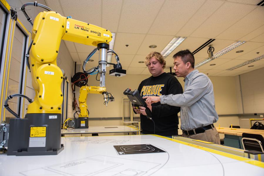 Student works in an engineering lab with a robotic arm.