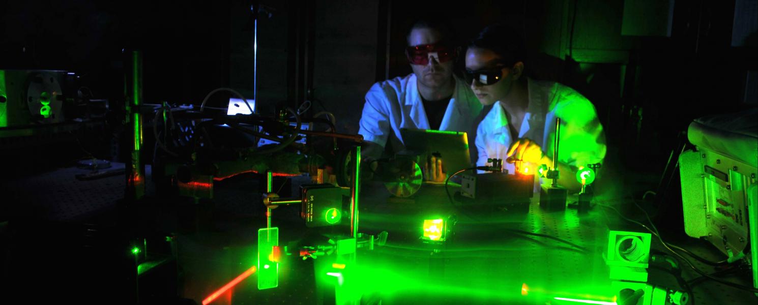 Physics student working with lasers in a laboratory setting.