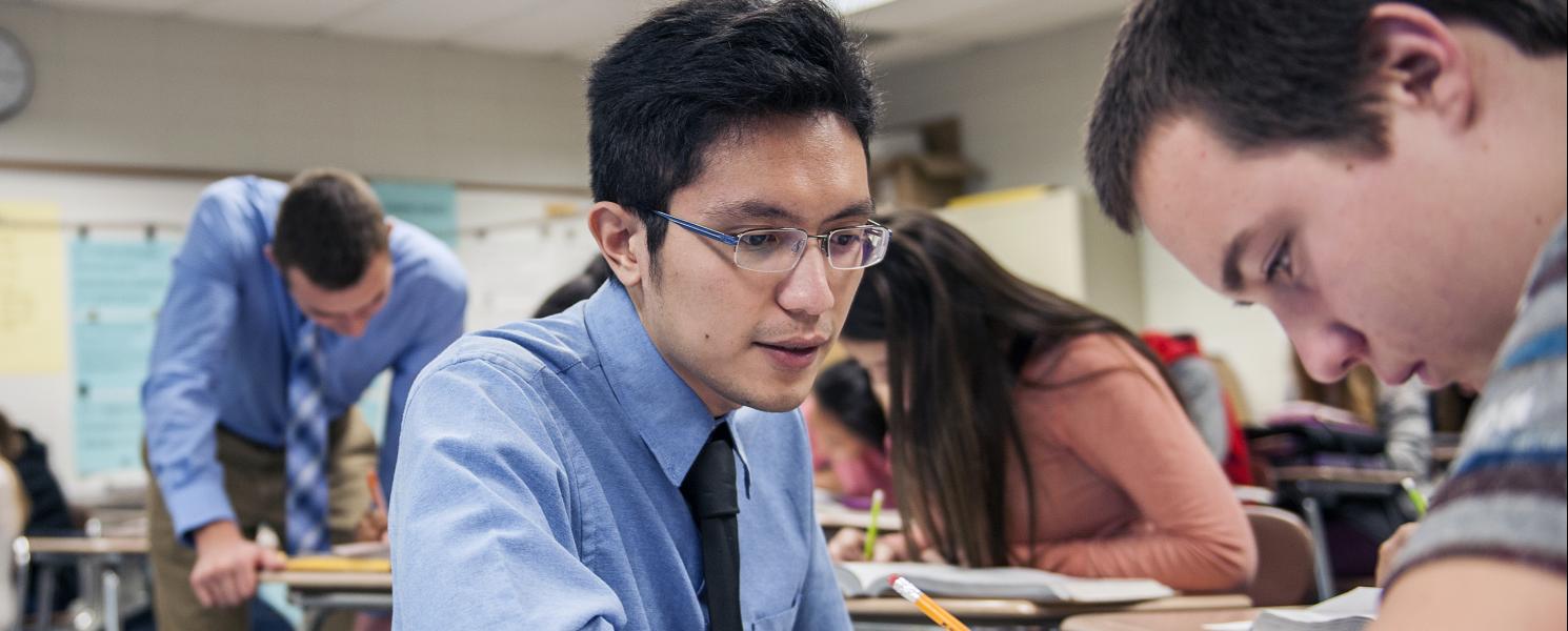 A male student teacher helps a high school student