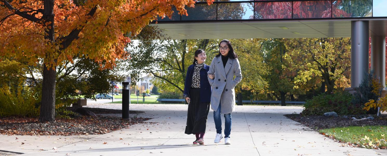 Two students walking on campus on an autumn afternoon.