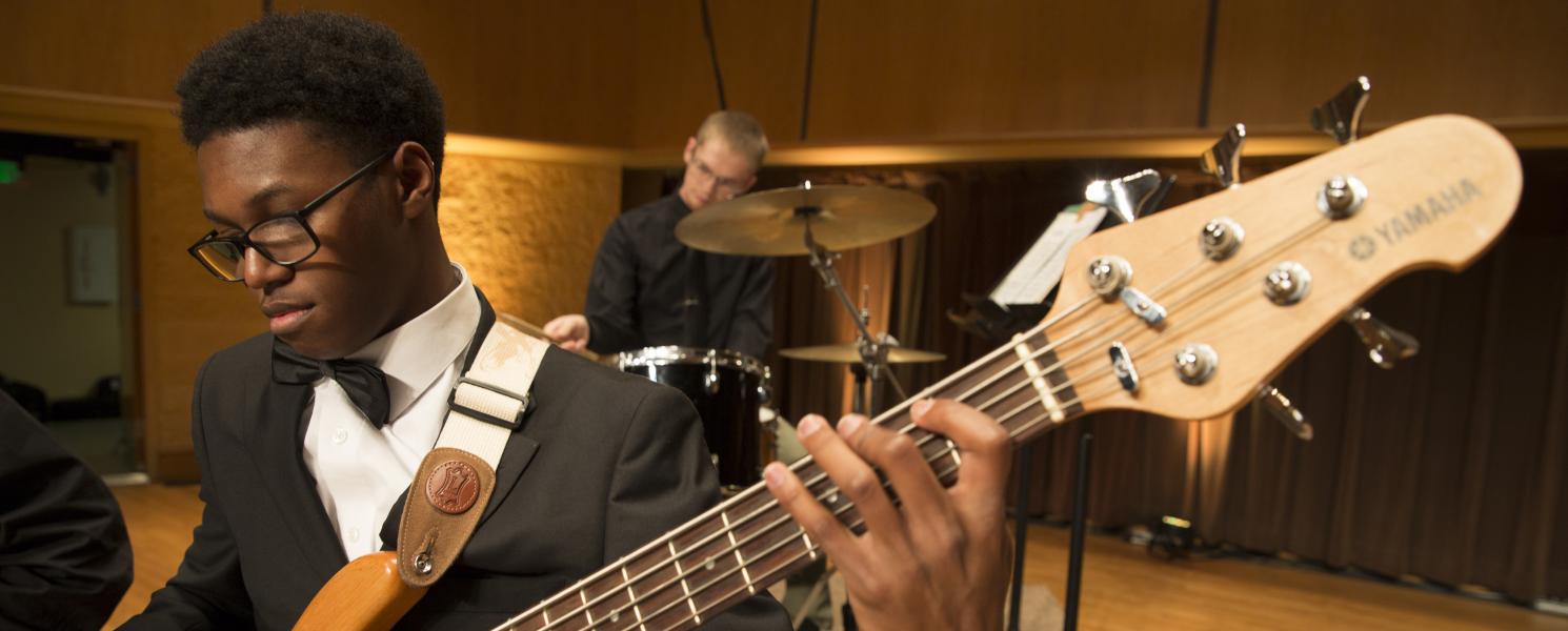 Student playing in a guitar in a concert.