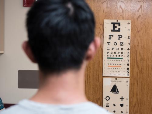 A patient stands in front of the eye exam chart at the clinic.