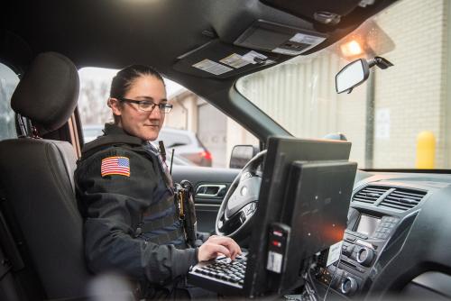 Police officer using a laptop in their vehicle.