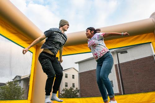 Students jumping in a bounce house at a Student Housing Event.