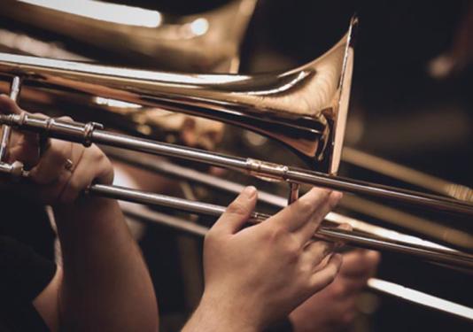 A close up of a hand playing a trombone.