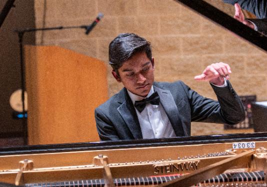 photo of young man playing grand piano