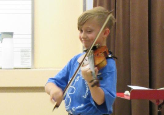 kid playing violin on stage