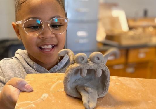 little kid holding clay sculpture.