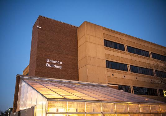 Science building at dusk with the greenhouse in the forefront.