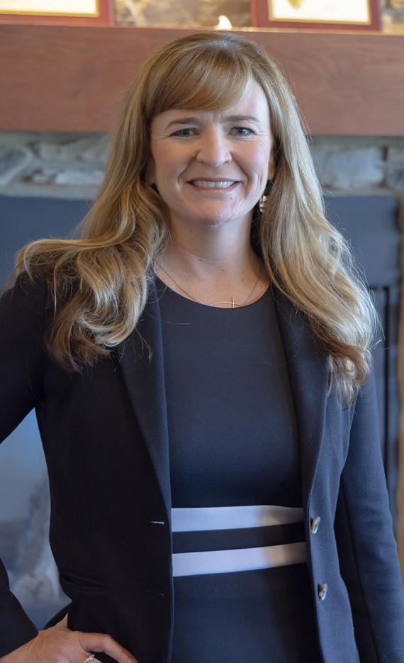 Portrait of Kim Grannan standing in front of a fireplace in the Alumni Center.