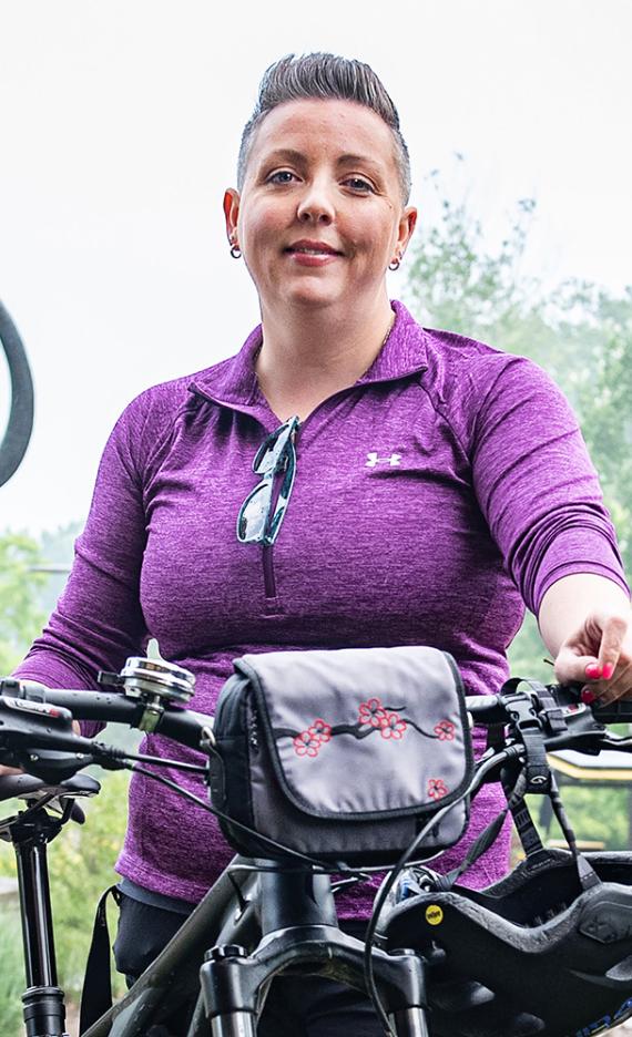 Teri Luce is standing in front of the mastodon statue with her bike.