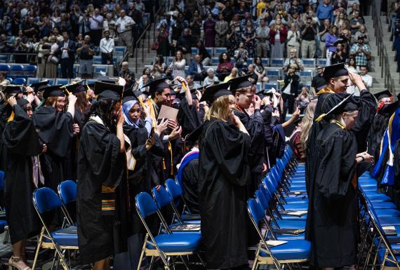 Students in caps and gowns standing at commencement.