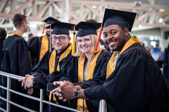 Students in caps and gowns smiling.