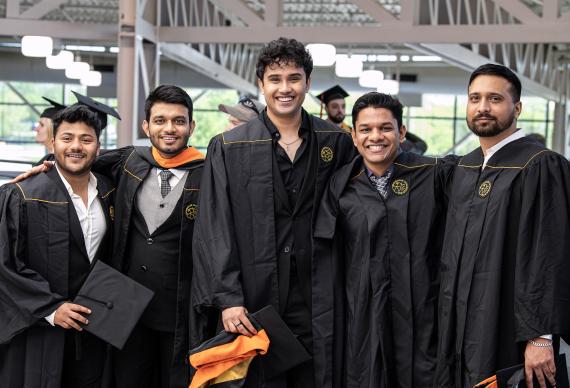 Graduate students pose in their commencement gowns.