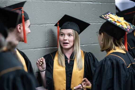 Graduating students chat in the hallway before commencement begins.