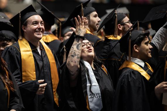 Graduating students wave to friends and guests in the crowd.