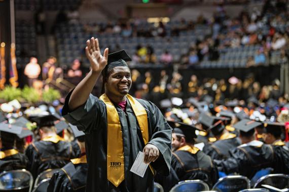 Graduating student waves to commencement guests.