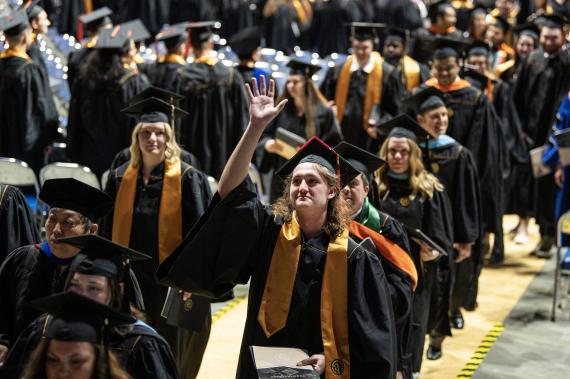 Graduating student waves to crowd.