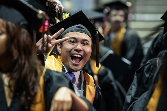 Graduating student holds up peace sign.