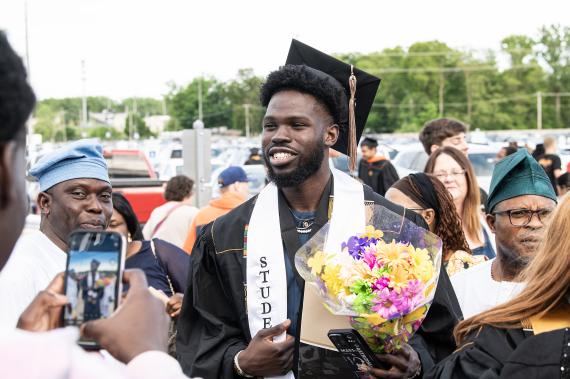 Graduated student athlete holding celebratory flowers.