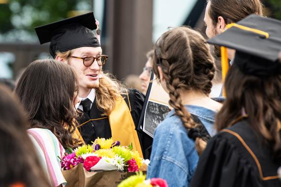 Graduates and commencement guests chat outside.