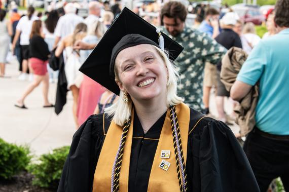 Student in cap and gown smiles at the camera.