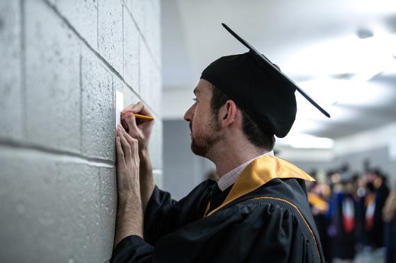 Student writes out name and degree on announcement card.