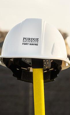 Construction helmet on a shovel with a backhoe in the background