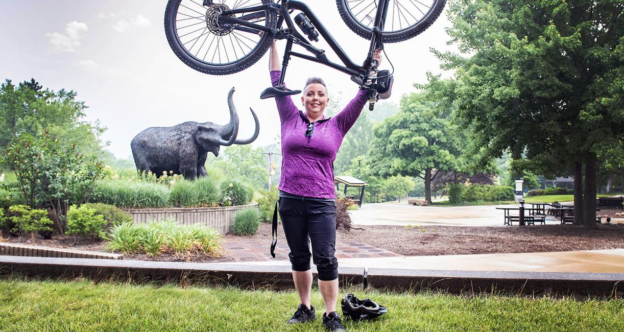 Teri Luce is hoisting a bicycle.