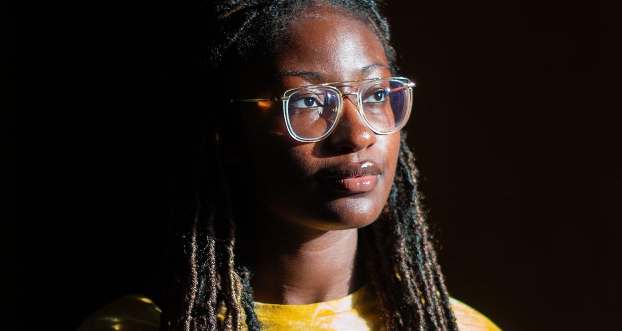 A young woman is in a dark room with natural lighting.